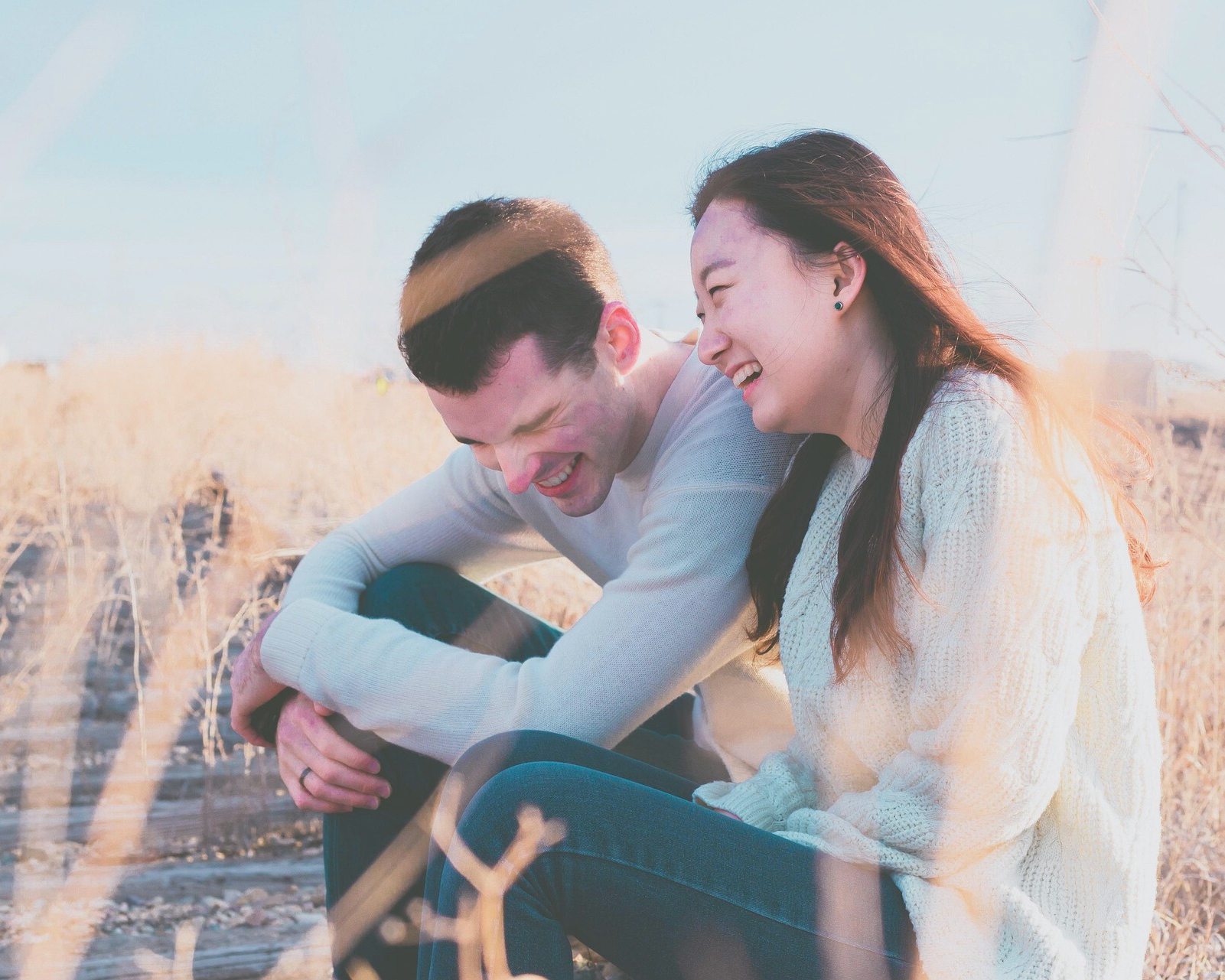 Happy People Field Smiling couple sitting outdoors in a sunlit field, sharing a joyful moment—symbolizing emotional renewal, connection, and the life-changing impact of ketamine and SPRAVATO therapy at Mind Rejuvenation, Tulsa’s trusted mental wellness clinic.