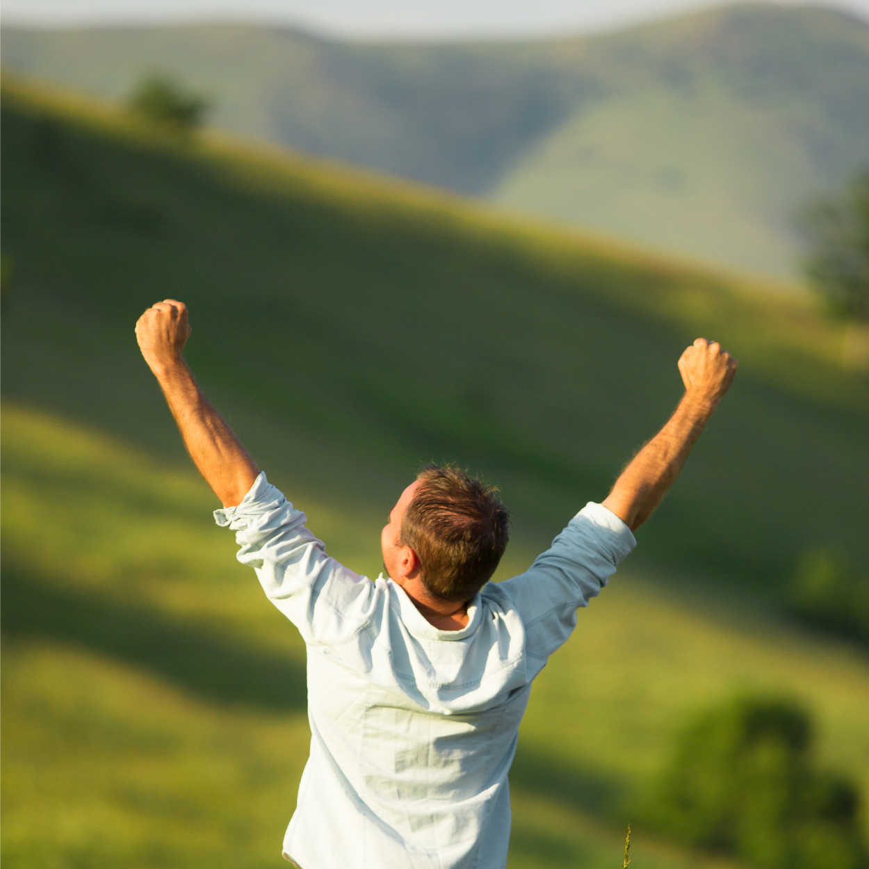 Ketamine IV Therapy Sq Person with arms raised in triumph against a lush green landscape, symbolizing emotional breakthrough and renewed vitality from Ketamine IV Therapy for depression, anxiety, and PTSD.